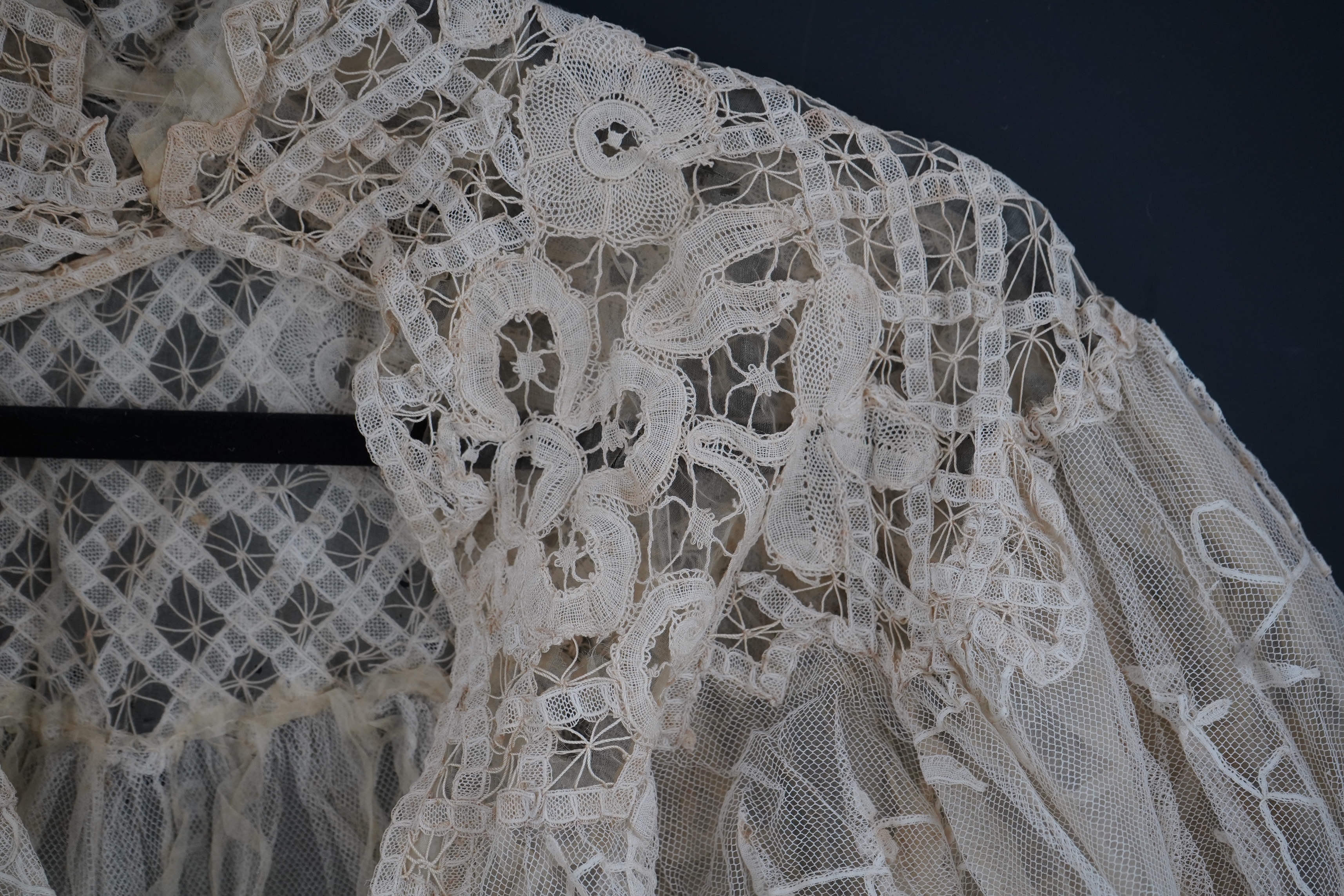 An Edwardian high collared cream tape lace wedding over blouse, made with a deep net frill and cream chiffon rose detail hanging from lower edge, top of collar to rose detail at the front 46cm. Condition - fine silk chif